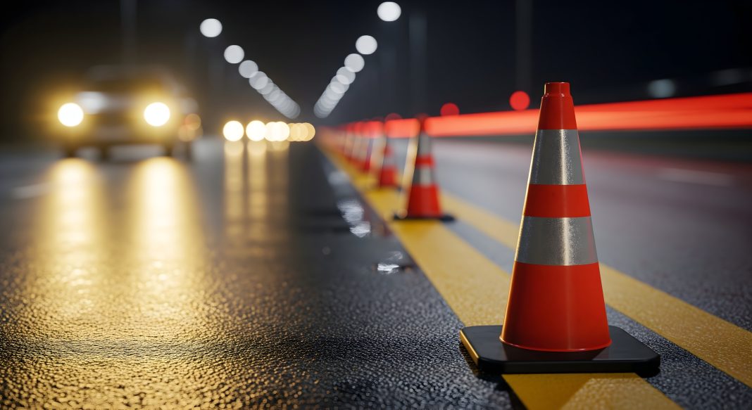 Orange traffic cones and warning signs marking a road construction work zone on a highway