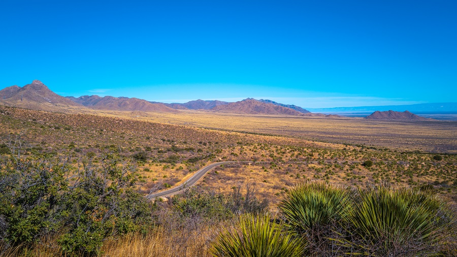 Organ Mountains, Desert Peaks National Monument in Las Cruces, Doña Ana County, New Mexico, Southwestern USA, tranquil arid desert land and plains with curved paved road and Yucca wilderness plants.