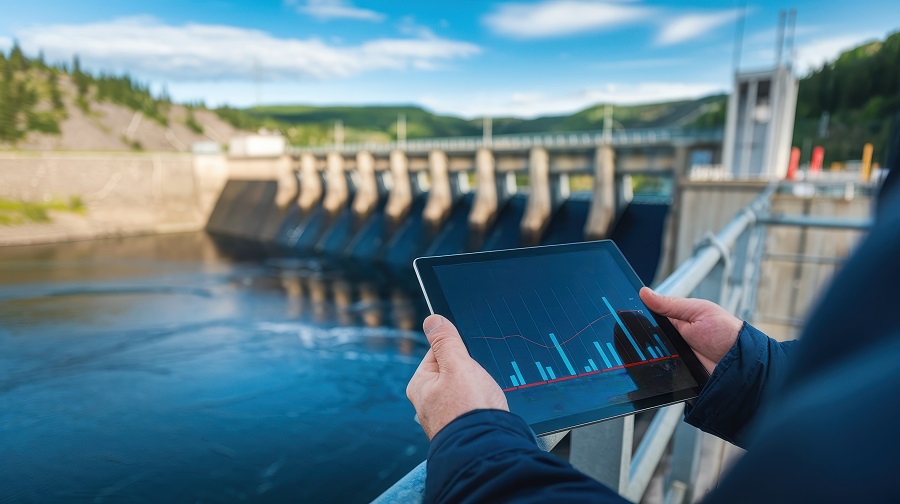 Impact of renewable energy sustainability jobs concepts. Person using a tablet to analyze data near a dam and water reservoir.
