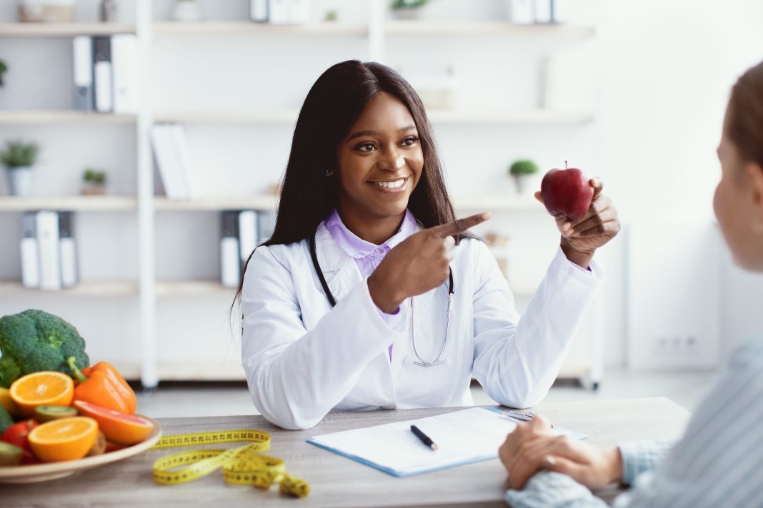 A doctor speaks with a patient in a New Mexico clinic, highlighting the physician’s call to address chronic disease prevention as part of solving the healthcare worker shortfall.