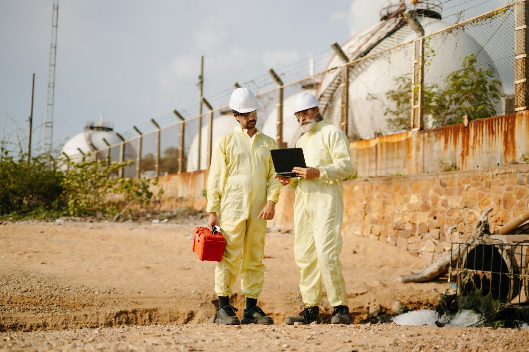Two engineers wearing protective gear test wastewater samples in a laboratory setting to identify viruses before clinical cases appear, supporting early detection and outbreak response.