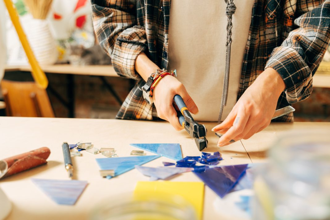 Participants craft stained‑glass hummingbird ornaments during a Santa Fe workshop, selecting colorful glass pieces and assembling them with Tiffany‑style techniques.