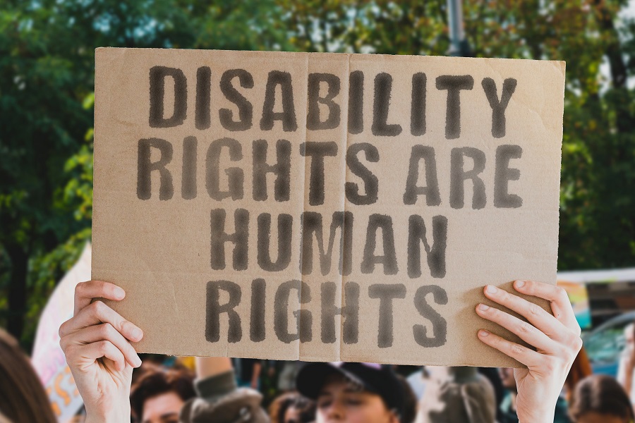 A powerful image of a man’s hand holding a banner with the text ‘Disability rights are human rights.’ Perfect for showcasing support or protest for the rights of people with disabilities worldwide