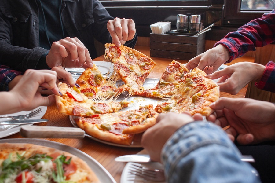 group of students friends eat Italian pizza, hands take slices of pizza in a restaurant, close-up