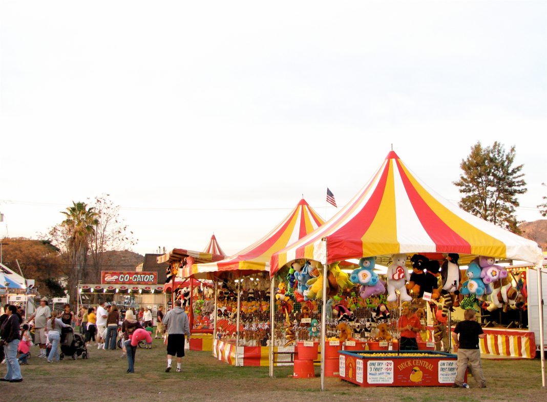 Families enjoying rides, games, and food at the Edgewood Carnival in New Mexico, with colorful lights and a festive atmosphere.