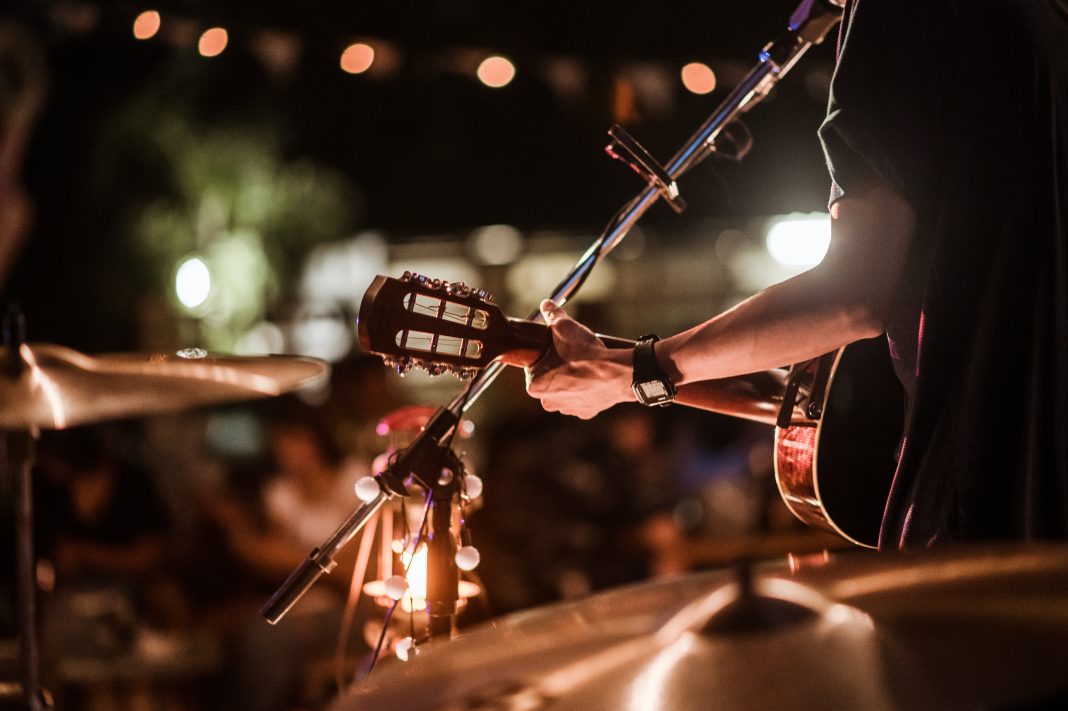 Musicians performing live blues at Albuquerque’s Patio Market during First Friday, with visitors enjoying art displays and refreshments.