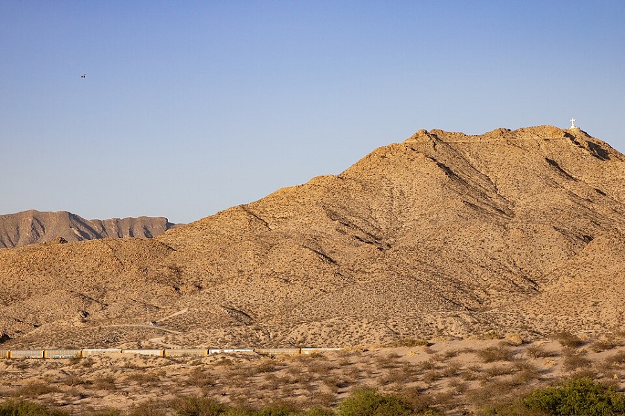 Texas Department of Public Safety (DPS) helicopter N329TX flies over an Autonomous Surveillance Tower (AST), manufactured by Anduril Industries and operated by U.S. Customs and Border Protection (CBP), on Mount Cristo Rey in Sunland Park, New Mexico, in May 2024.