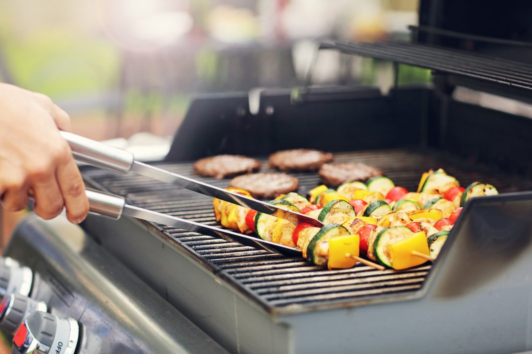 A family grills outdoors during a Fourth of July cookout while following recommended fire safety practices.
