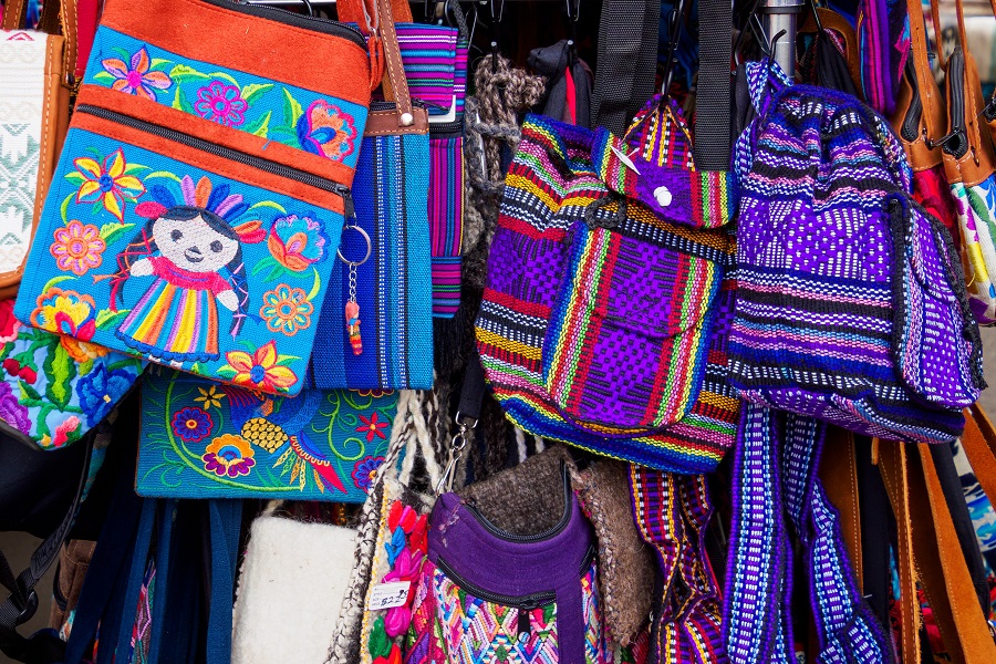 Fabric bags for sale at a roadside mall in Santa Fe, NM, with bold floral and other embroidered designs