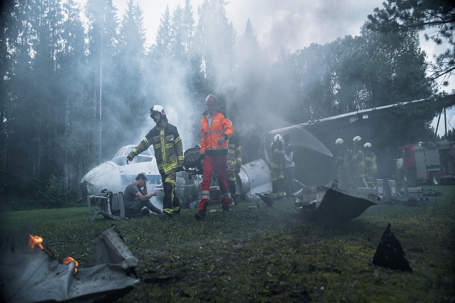 Smoke Blankets a Forest Plane Crash as Firefighters and Medics Search Shattered Airplane Wreckage, Control Small Fires, and Assist Survivors Near the Broken Fuselage, Debris